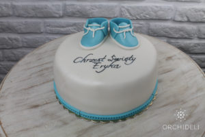 biały tort na chrzciny z niebieskimi bucikami z lukru plastycznego