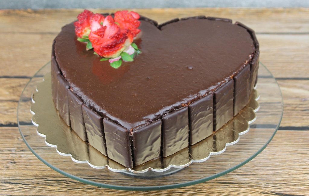 Tort red velevet w kształcie serca, polany czekoladą, orchideli tort w kształcie serca polany czekoladą mleczną z dekoracją ze świeżych truskawek
